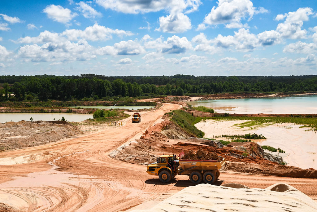 Landscape shot of the mine with large blue pools and dump trucks
