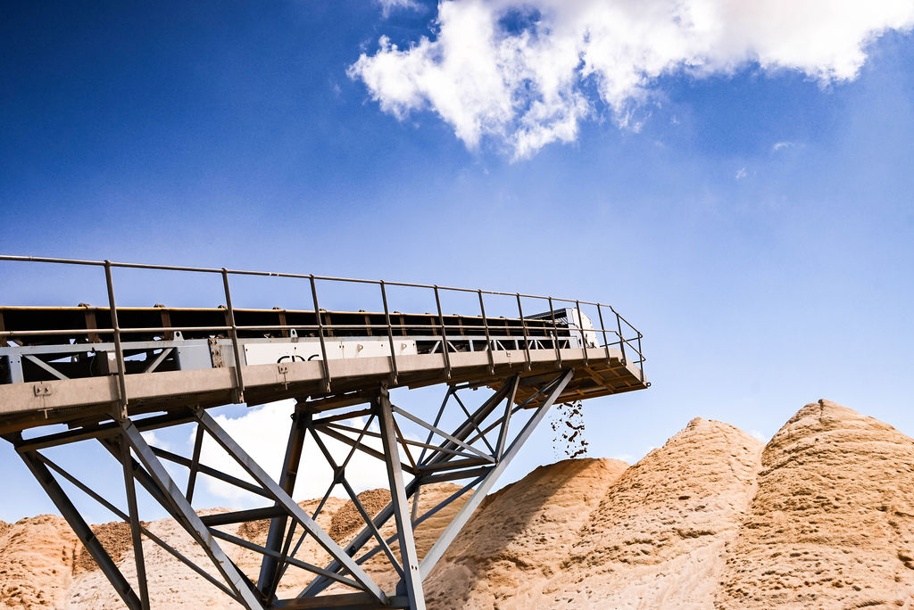 Machinery moving sand upward into a tall pile